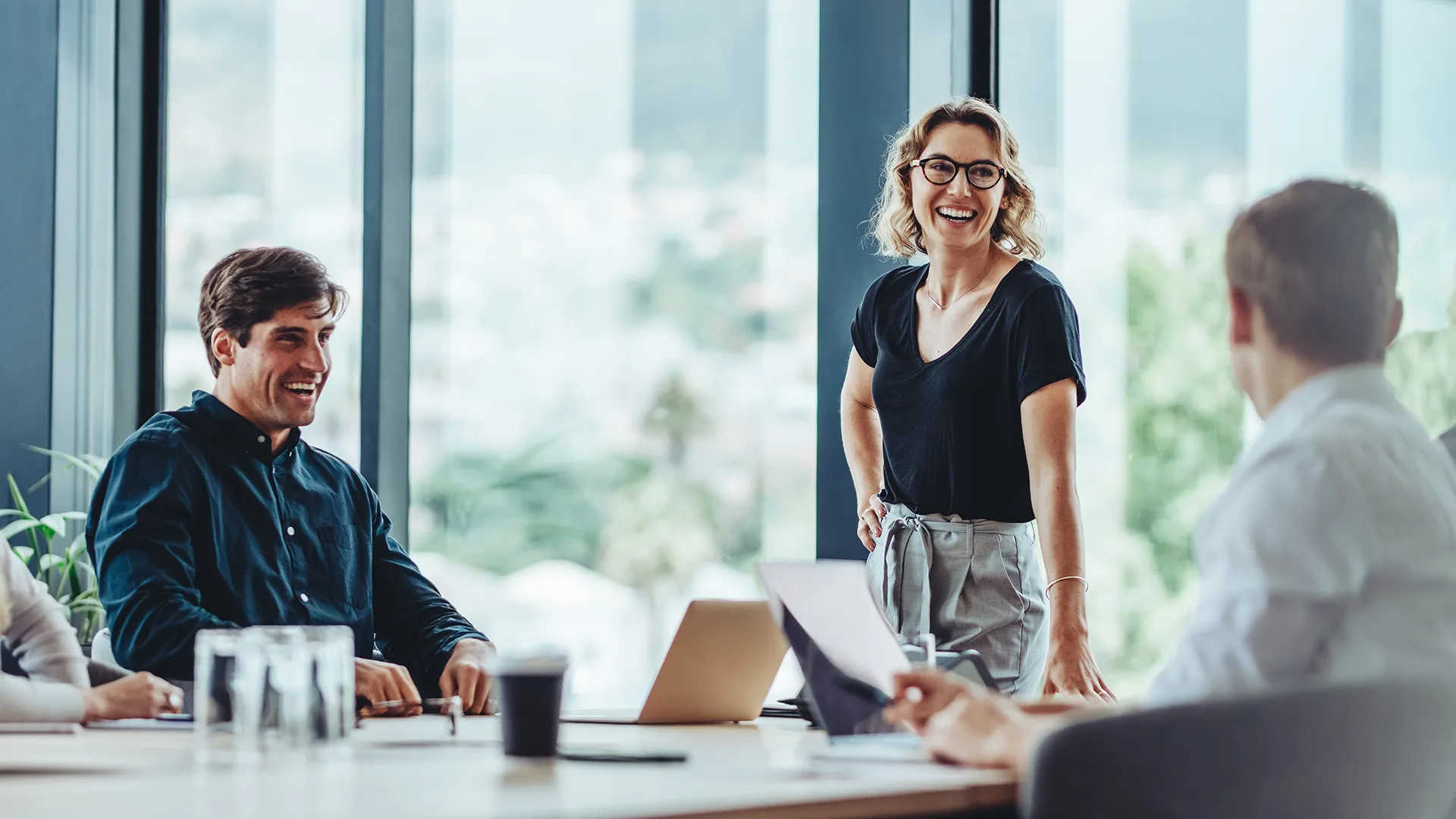 Group of colleagues engaging in a discussion during a business meeting in a conference room. Happy business people, men and women, collaborating and working towards their shared goals.